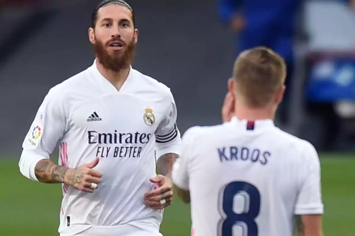 Dos jugadores de fútbol del Real Madrid en el campo, uno de ellos con el número 8 y el nombre "Kroos" en la camiseta.