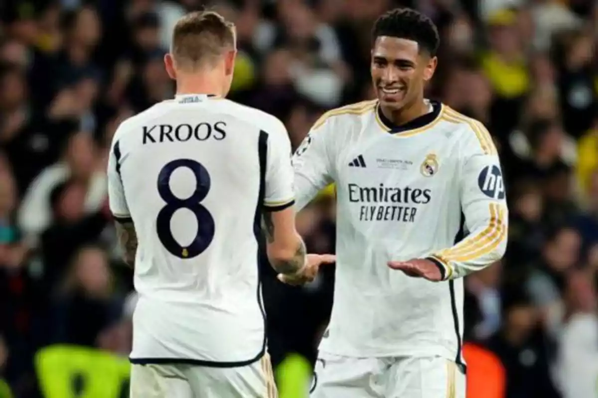 Dos jugadores de fútbol del Real Madrid celebran en el campo, uno de ellos lleva el número 8 y el nombre "Kroos" en su camiseta.