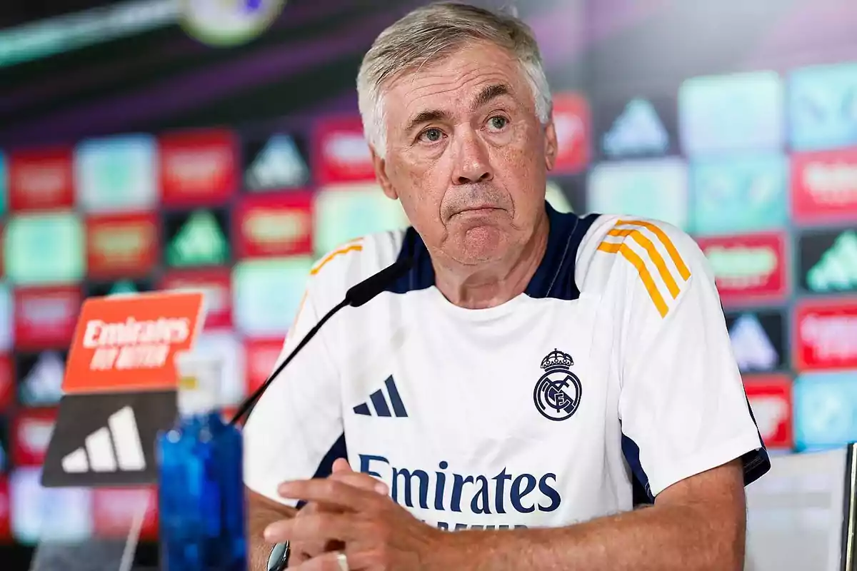 Un hombre con camiseta de entrenamiento del Real Madrid en una conferencia de prensa.