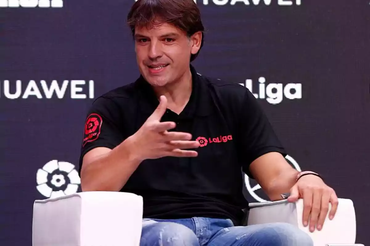 Un hombre con una camiseta negra de LaLiga está sentado en una silla blanca, gesticulando con la mano mientras habla, con un fondo que muestra logotipos de Huawei y LaLiga.