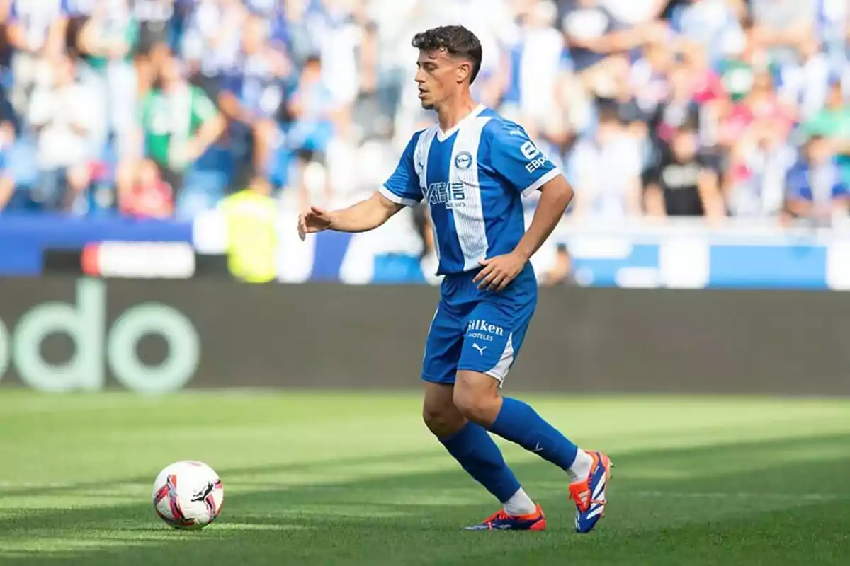 Un jugador de fútbol con uniforme azul y blanco en el campo durante un partido. Un jugador de fútbol con uniforme azul y blanco en el campo durante un partido.