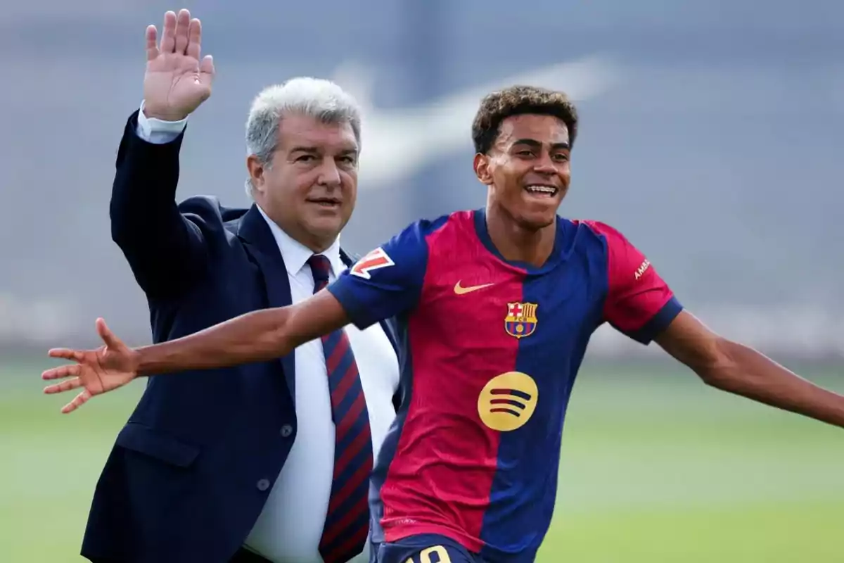 Un hombre en traje saluda mientras un jugador de fútbol con uniforme del Barcelona sonríe y extiende los brazos.