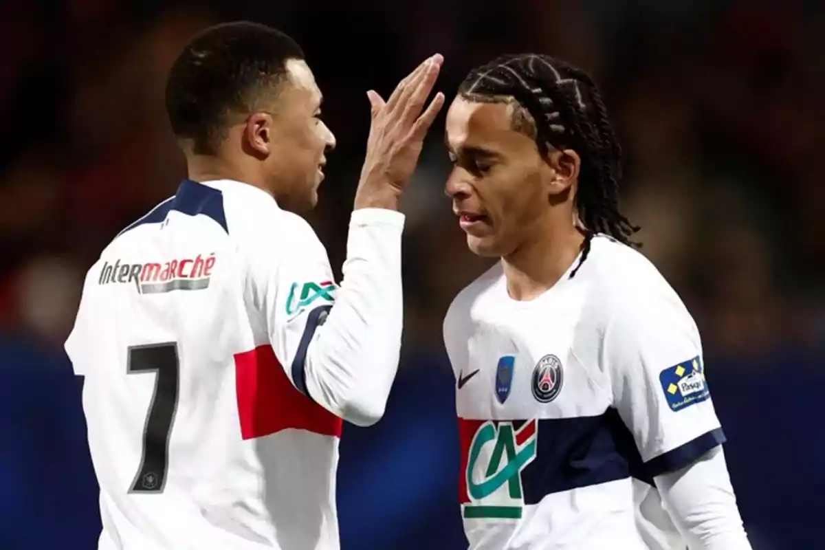 Dos jugadores de fútbol del PSG interactuando en el campo durante un partido.