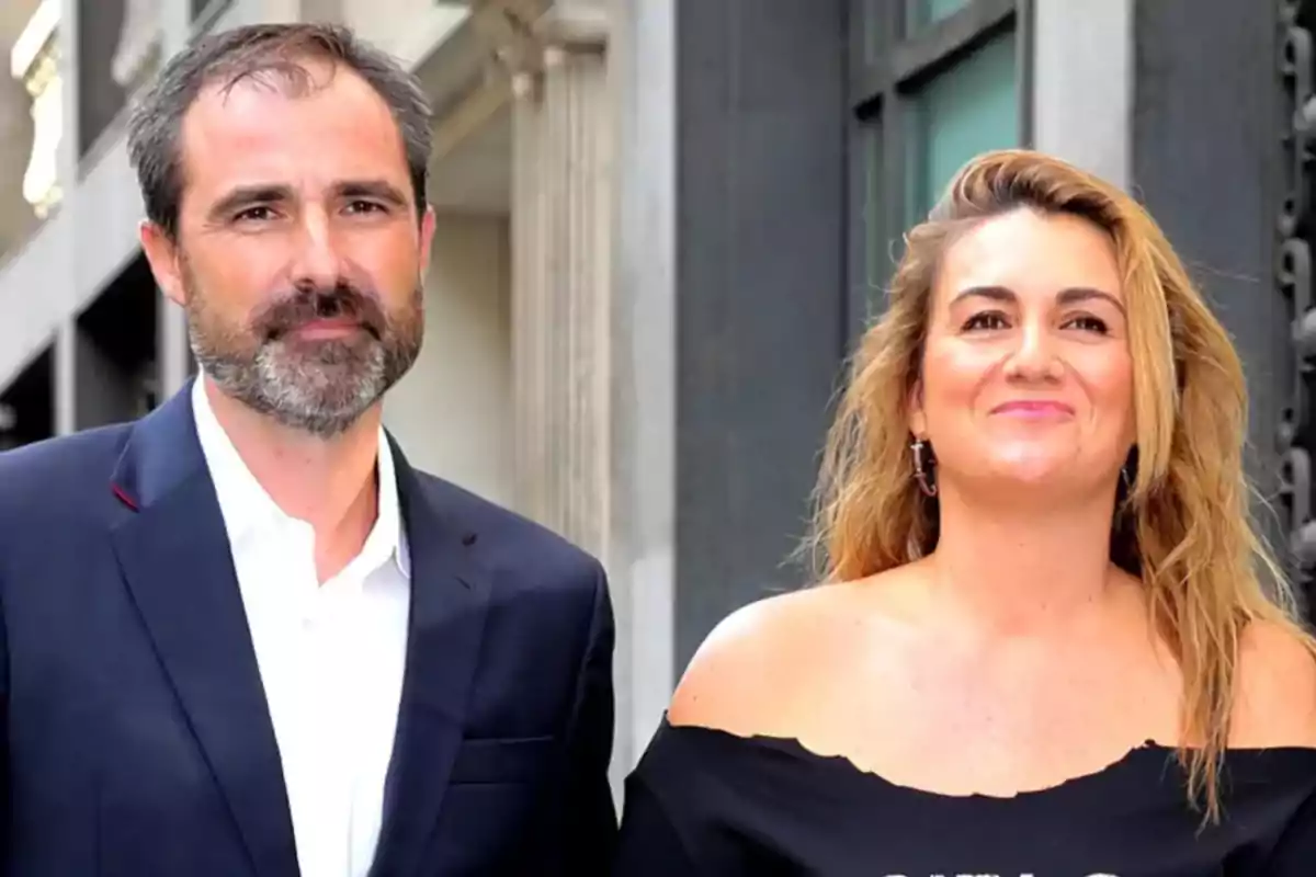 Dos personas posando juntas en una calle con edificios de fondo.