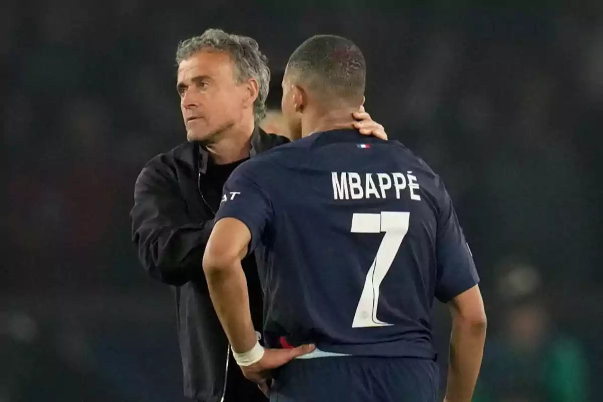 Un entrenador de fútbol hablando con un jugador que lleva la camiseta número 7 con el nombre "Mbappé" en la espalda.