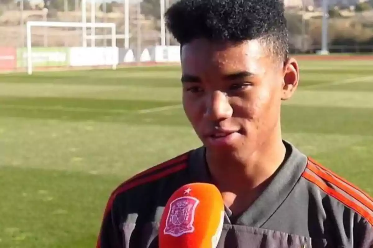 Un joven futbolista siendo entrevistado en un campo de fútbol.