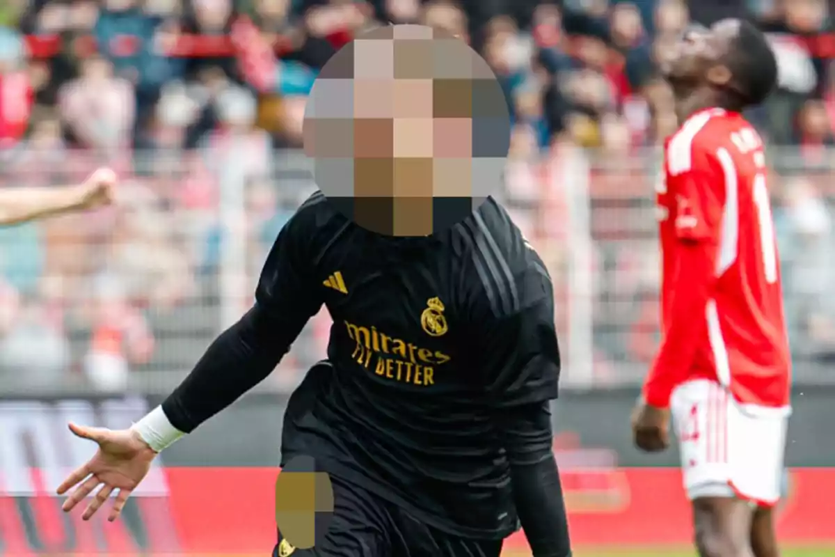 Un jugador de fútbol con uniforme negro celebra mientras otro jugador con uniforme rojo y blanco parece decepcionado en el fondo.