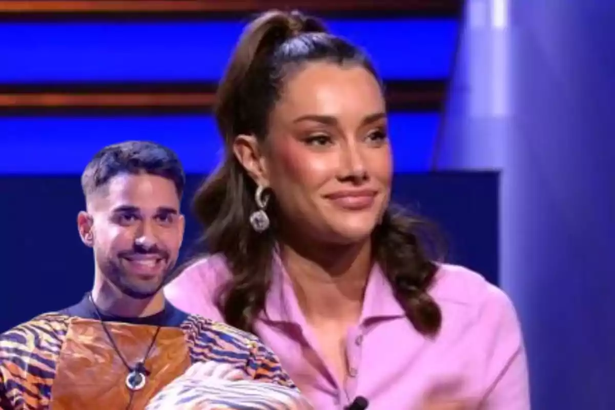 Una mujer con camisa rosa y un hombre con camiseta de rayas sonríen en un set de televisión iluminado en azul.