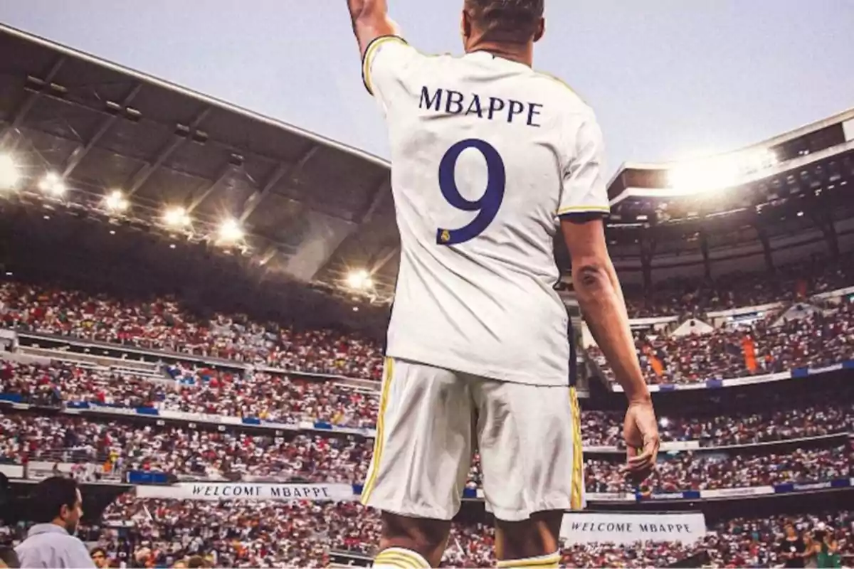 Un jugador de fútbol con la camiseta número 9 y el nombre "Mbappe" levantando el brazo en un estadio lleno de espectadores.