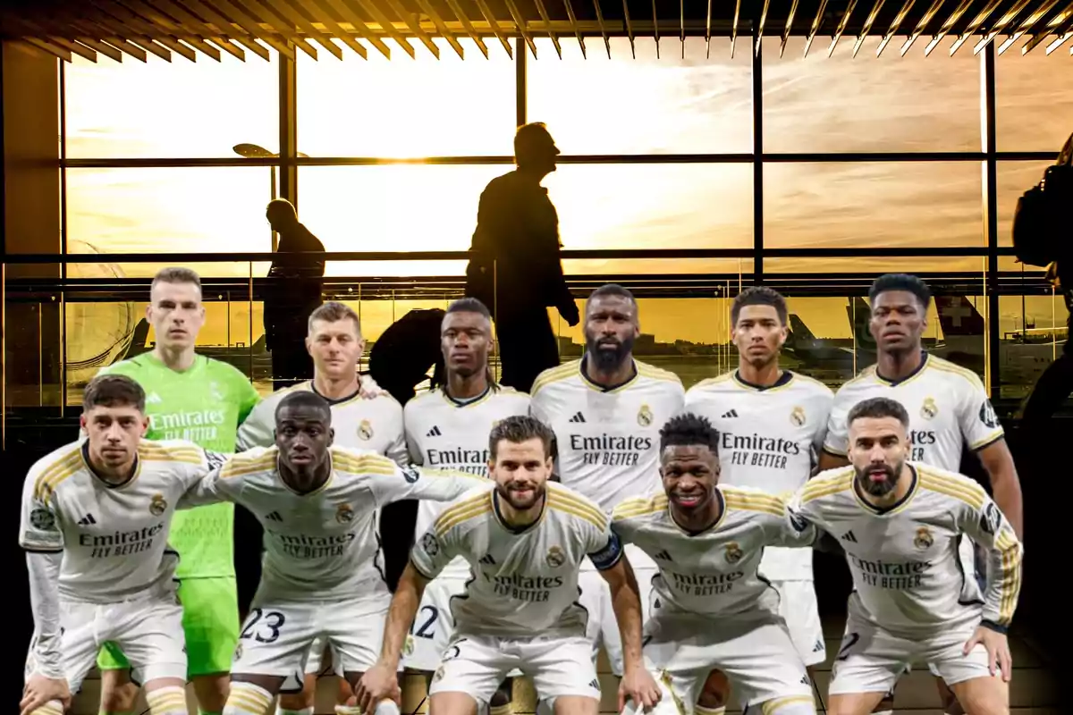 Jugadores de fútbol posando en un aeropuerto con el atardecer de fondo.