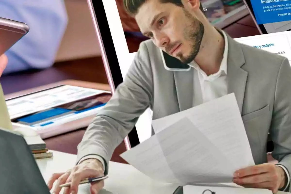 Hombre multitarea hablando por teléfono mientras revisa documentos y usa una computadora portátil.