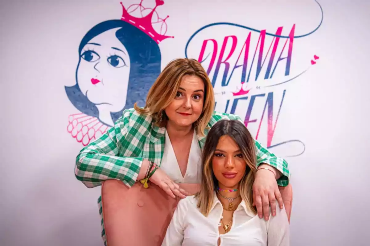 Dos mujeres posan frente a un fondo con un dibujo de una caricatura y las palabras Dos mujeres posan frente a un fondo con un dibujo de una caricatura y las palabras