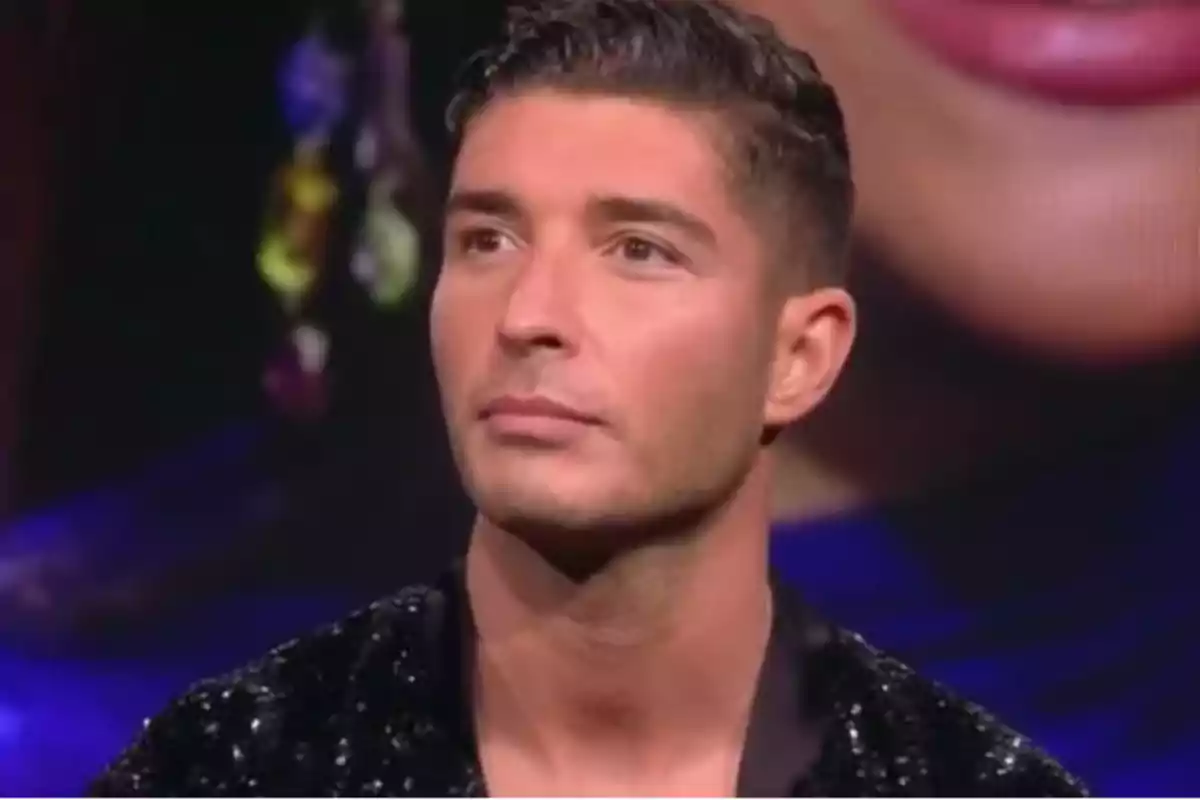 Un hombre con cabello corto y expresión seria en un entorno iluminado. Un hombre con cabello corto y expresión seria en un entorno iluminado.
