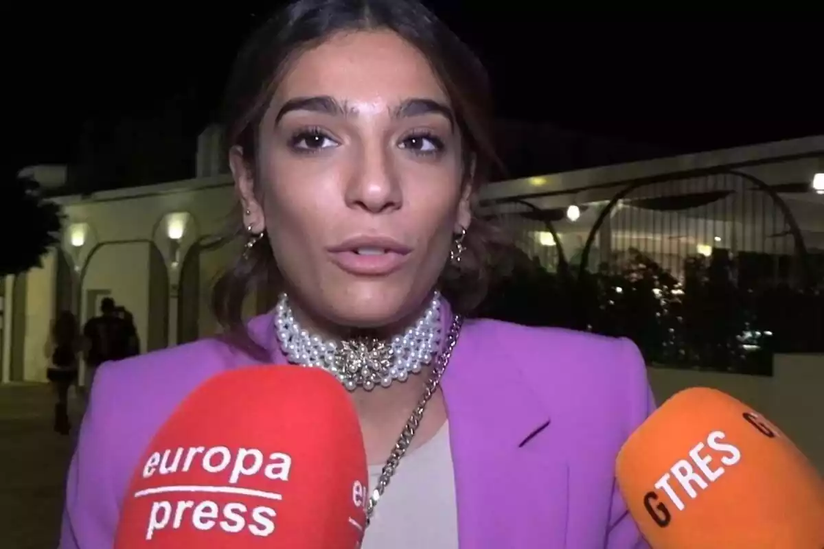 Alma Bollo con un collar de perlas hablando con la prensa en la calle