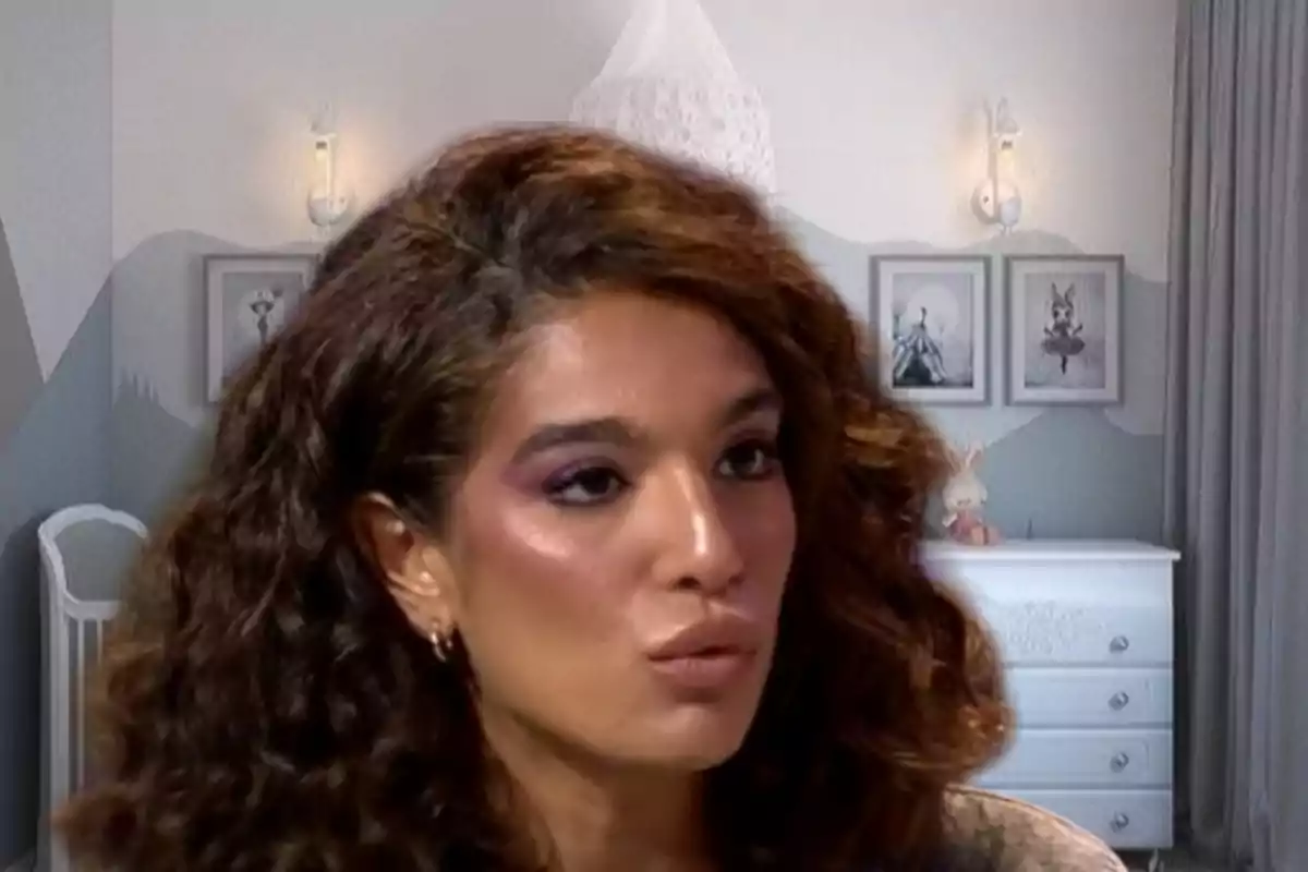 Una persona con cabello rizado y maquillaje en un entorno interior decorado con muebles y cuadros.