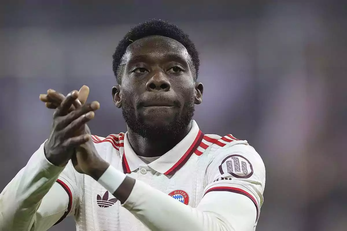 Un jugador de fútbol aplaudiendo en el campo con una camiseta blanca y detalles rojos.