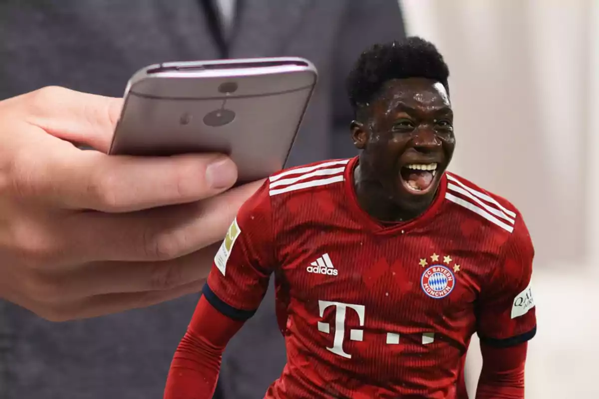 Un hombre sosteniendo un teléfono móvil con la imagen de un jugador de fútbol del Bayern de Múnich celebrando en primer plano.