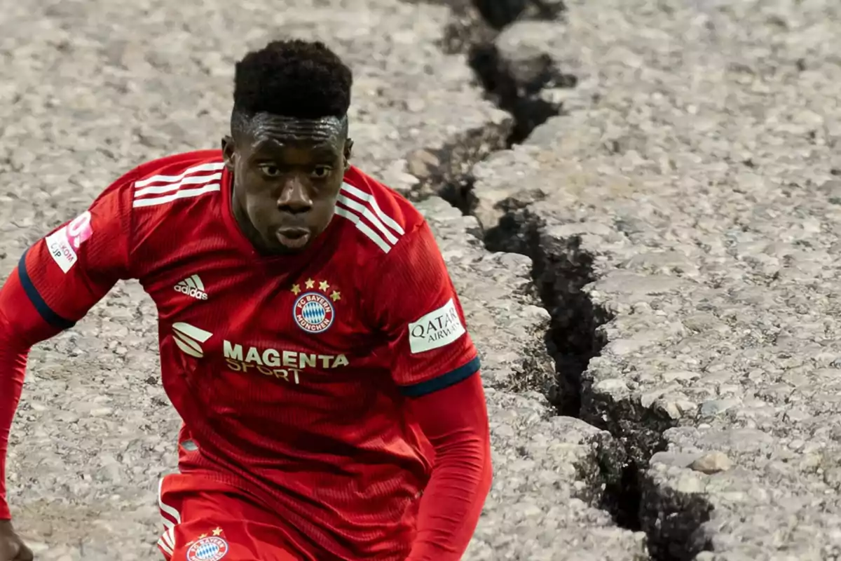 Jugador de fútbol con uniforme rojo del Bayern Múnich en un campo con grietas en el suelo.