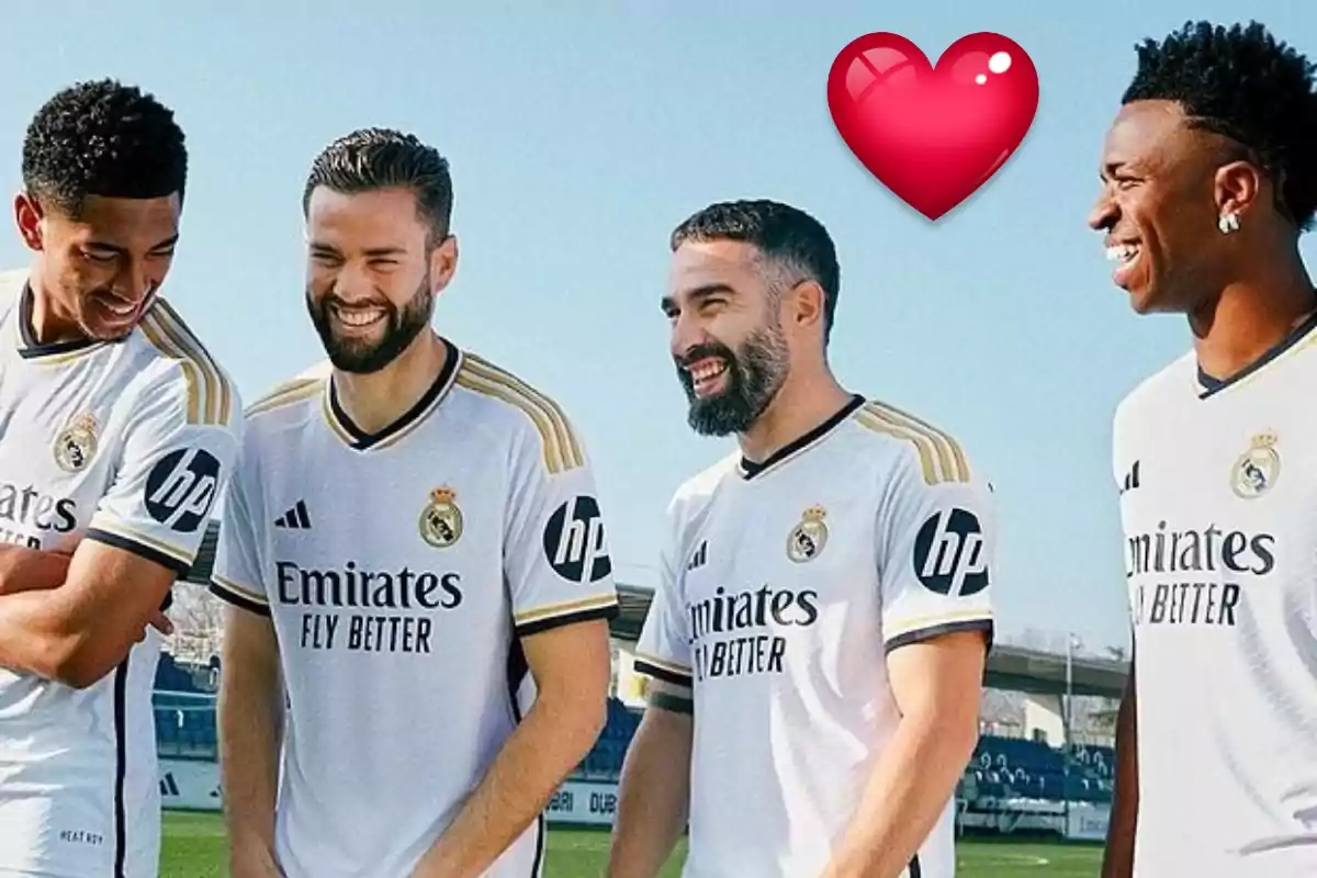 Jugadores de fútbol del Real Madrid sonriendo y conversando mientras usan el uniforme del equipo, con un emoji de corazón rojo en la esquina superior derecha.