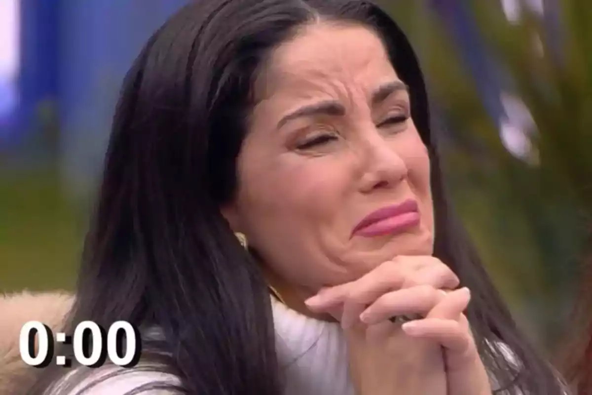 Mujer con expresión emocional intensa y manos juntas, con un cronómetro en la esquina inferior izquierda mostrando 0:00. Mujer con expresión emocional intensa y manos juntas, con un cronómetro en la esquina inferior izquierda mostrando 0:00.