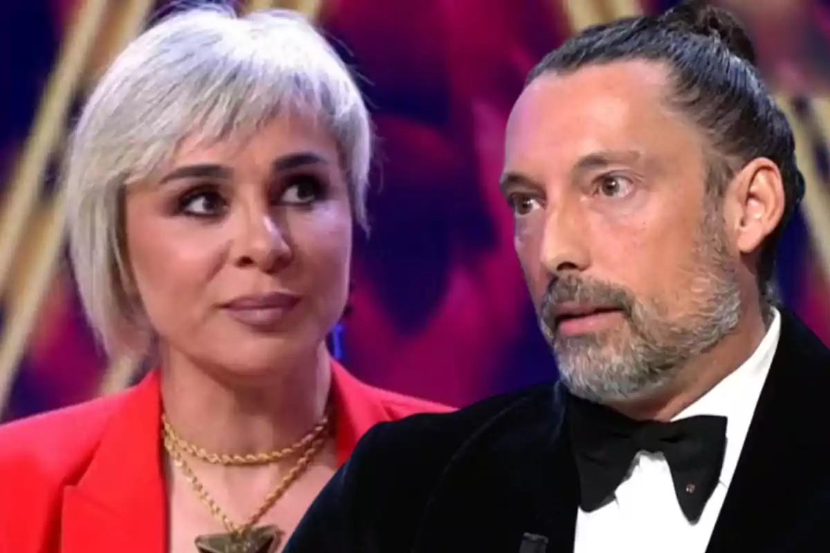 Dos personas en un programa de televisión con expresiones serias y un fondo colorido.