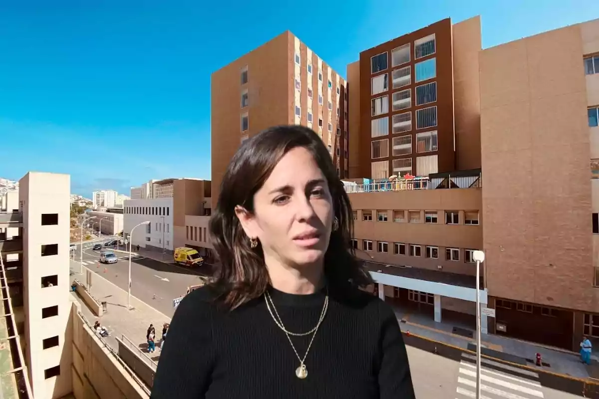 Una mujer de cabello oscuro está frente a un edificio grande de ladrillo en un día soleado.