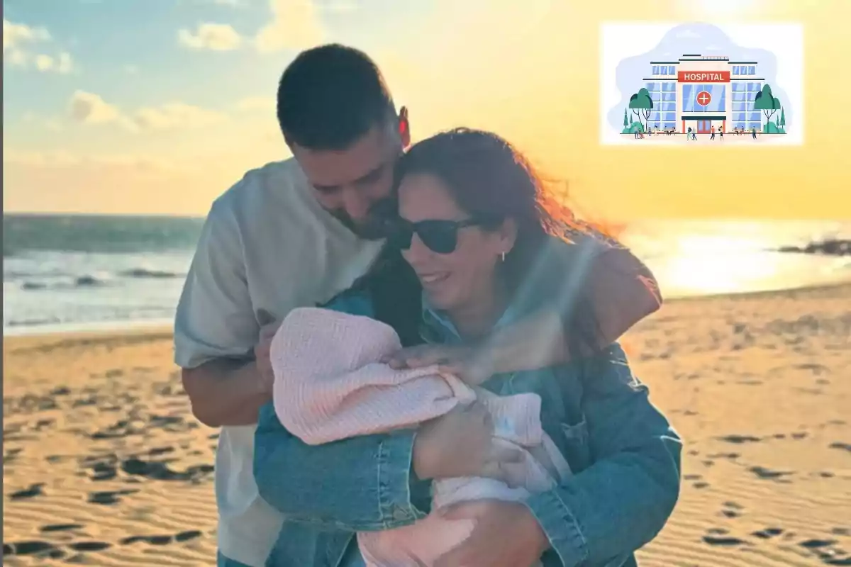 Una pareja sonriente sostiene a un bebé envuelto en una manta en la playa al atardecer.