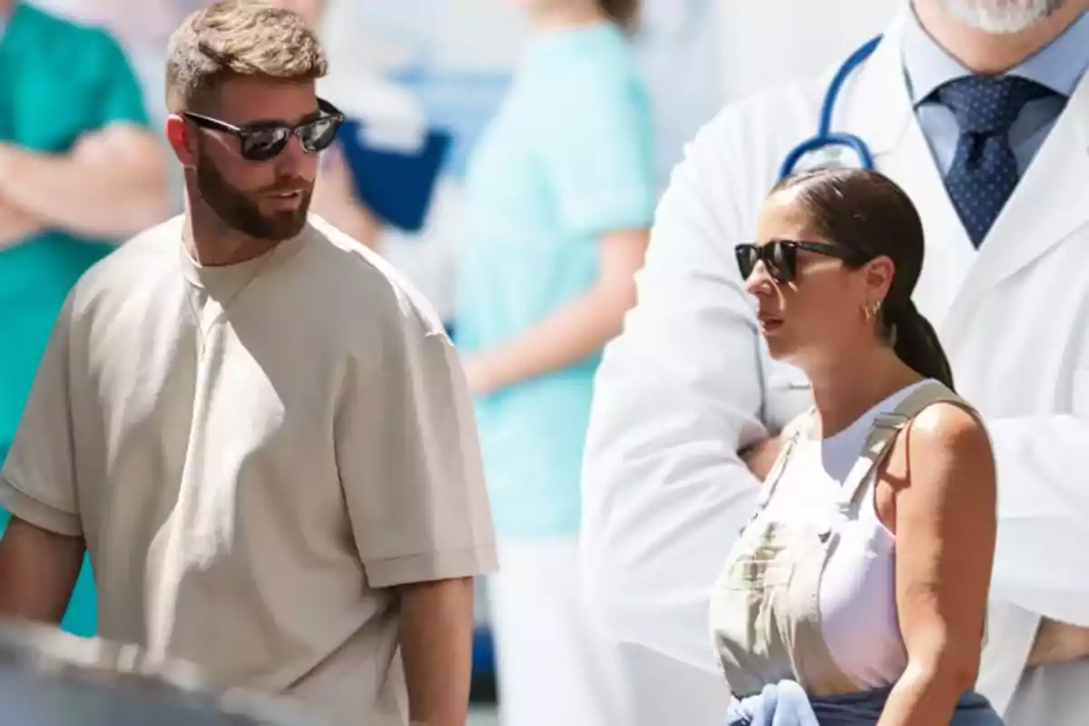 Dos personas con gafas de sol caminan al aire libre, mientras al fondo se ve una imagen de un médico con bata blanca y estetoscopio.