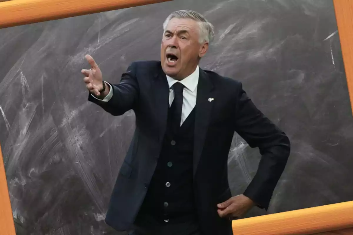 Un hombre de cabello canoso, vestido con traje oscuro y corbata, gesticula con la mano mientras parece estar hablando apasionadamente, con un fondo de pizarra detrás de él.