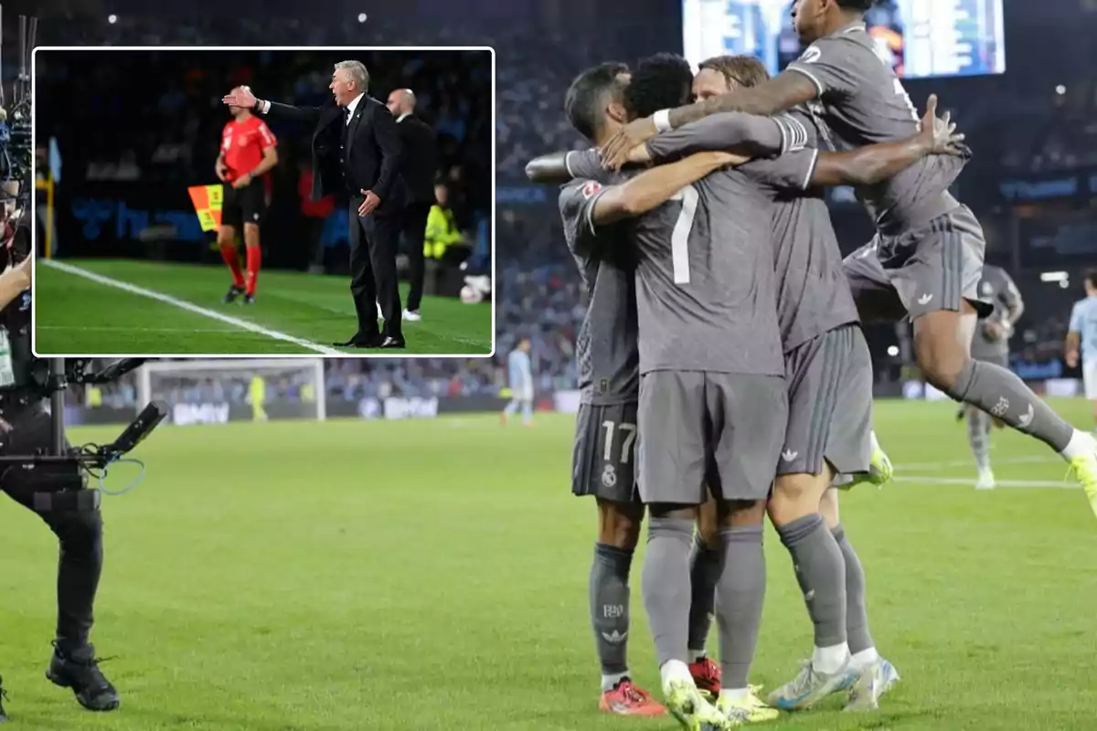 Un grupo de jugadores de fútbol celebra un gol en el campo mientras un entrenador da instrucciones desde la línea lateral.