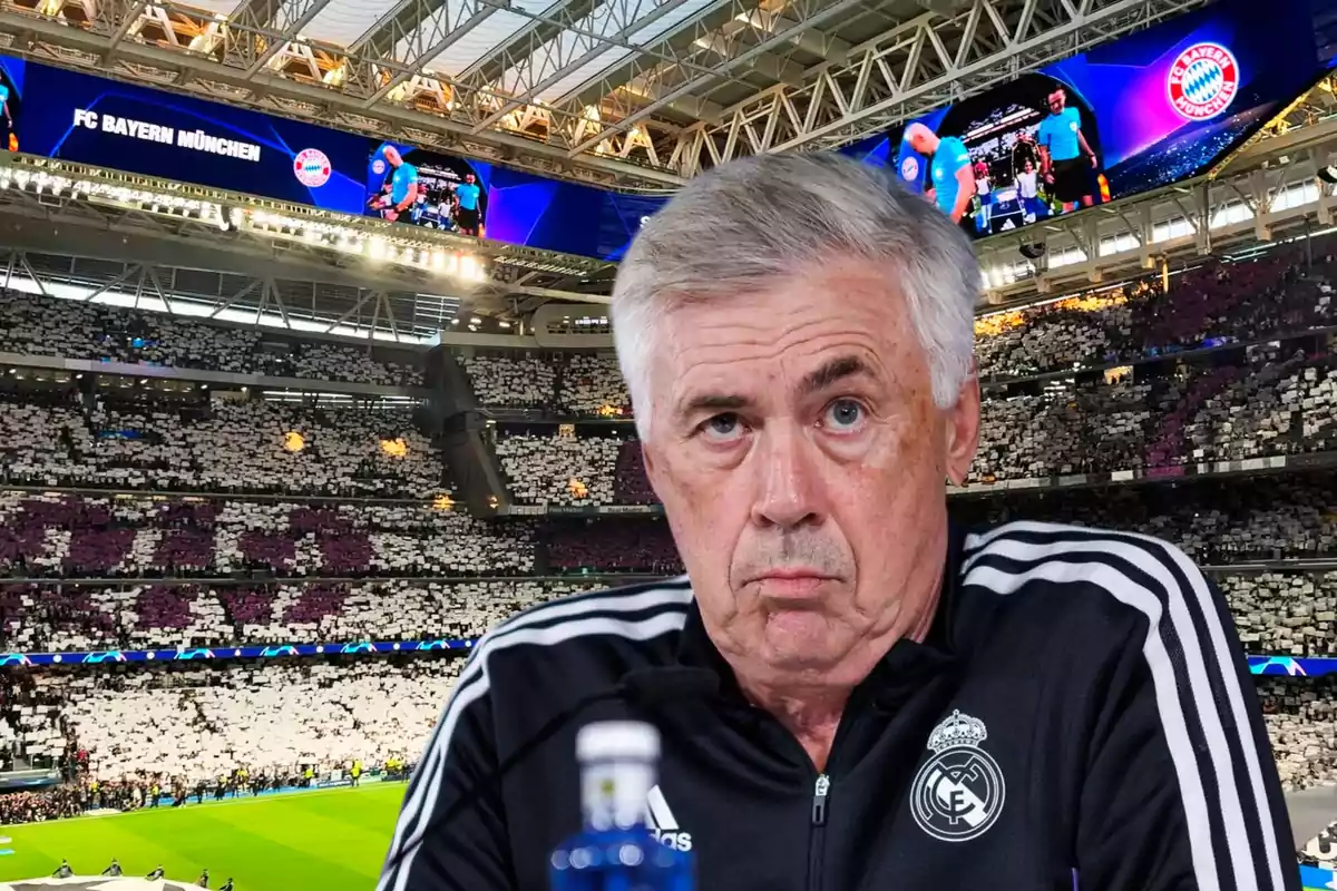 Un hombre con chaqueta deportiva del Real Madrid en un estadio lleno de espectadores con pantallas que muestran el logo del FC Bayern München.