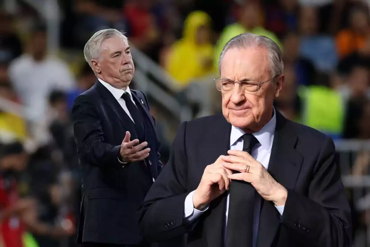 Dos hombres de traje oscuro en un evento deportivo, uno de ellos ajustándose la corbata.