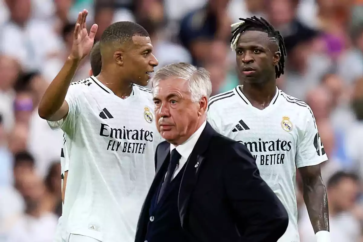 Tres personas con uniformes de fútbol blanco en un estadio.