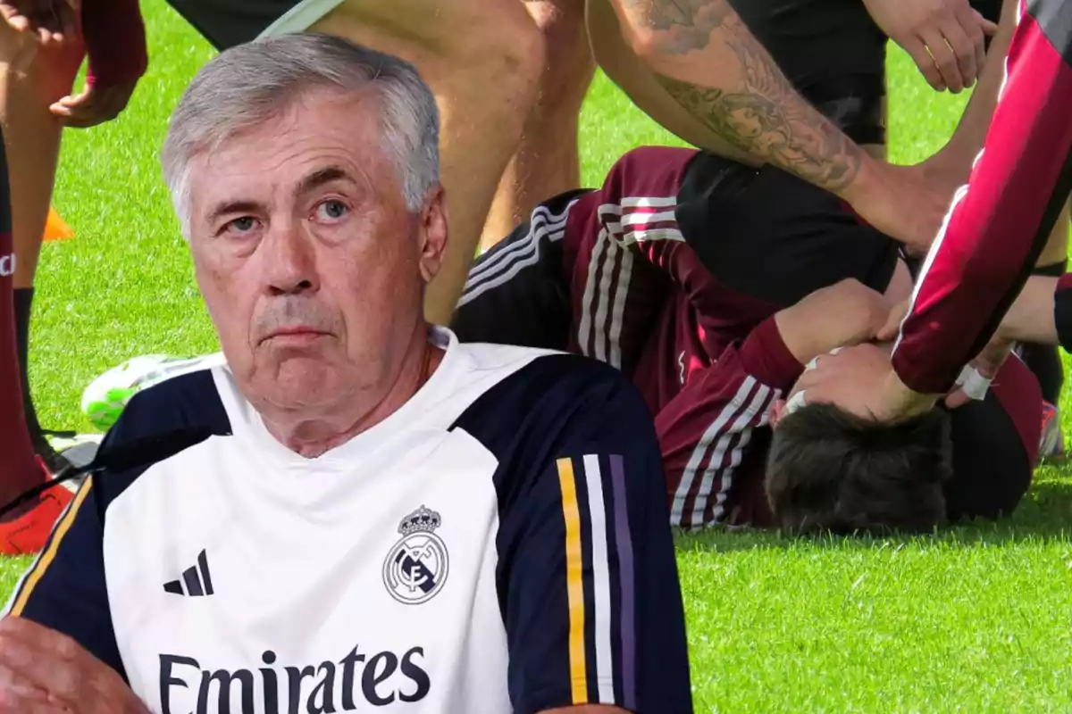 Carlo Ancelotti con la sudadera del Real Madrid y cara de preocupación, y de fondo un jugador tumbado en el césped con gestos de dolor por una lesión