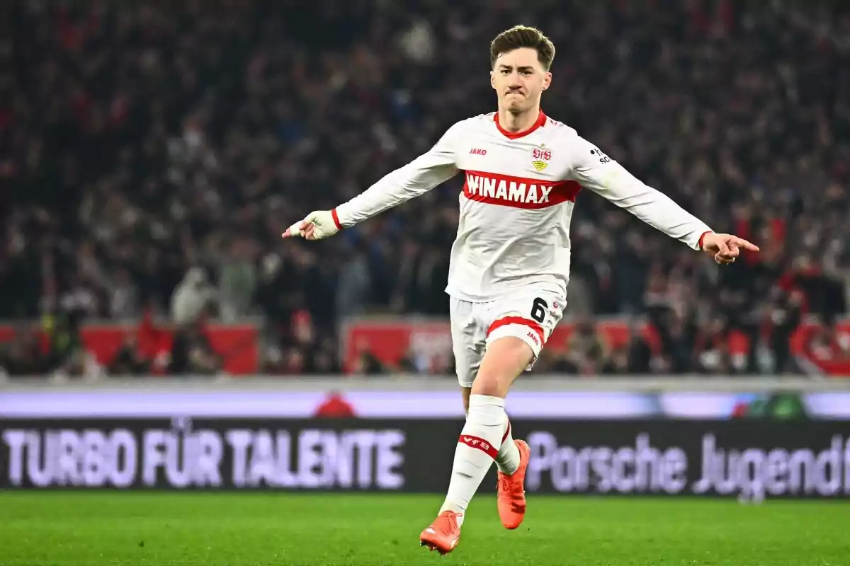 Futbolista con uniforme blanco celebrando un gol en un estadio lleno de espectadores Futbolista con uniforme blanco celebrando un gol en un estadio lleno de espectadores