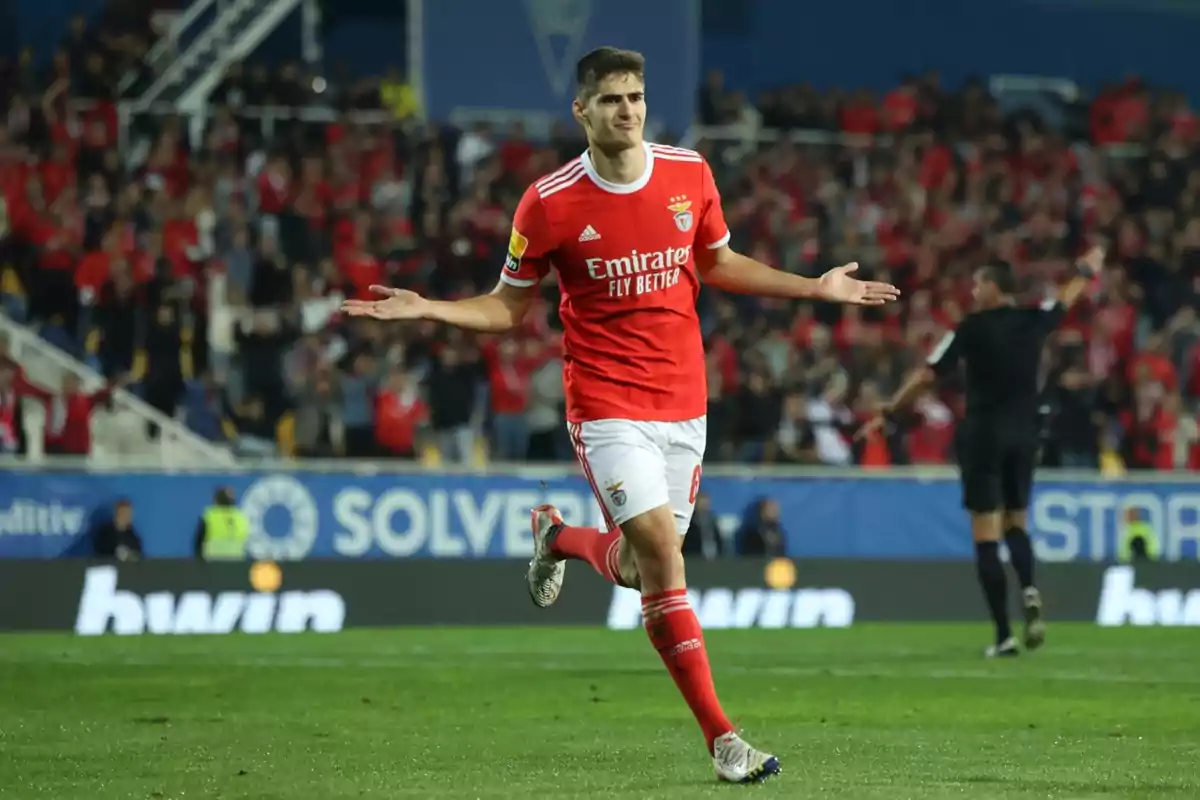 Jugador de fútbol celebrando un gol en un estadio lleno de aficionados. Jugador de fútbol celebrando un gol en un estadio lleno de aficionados.