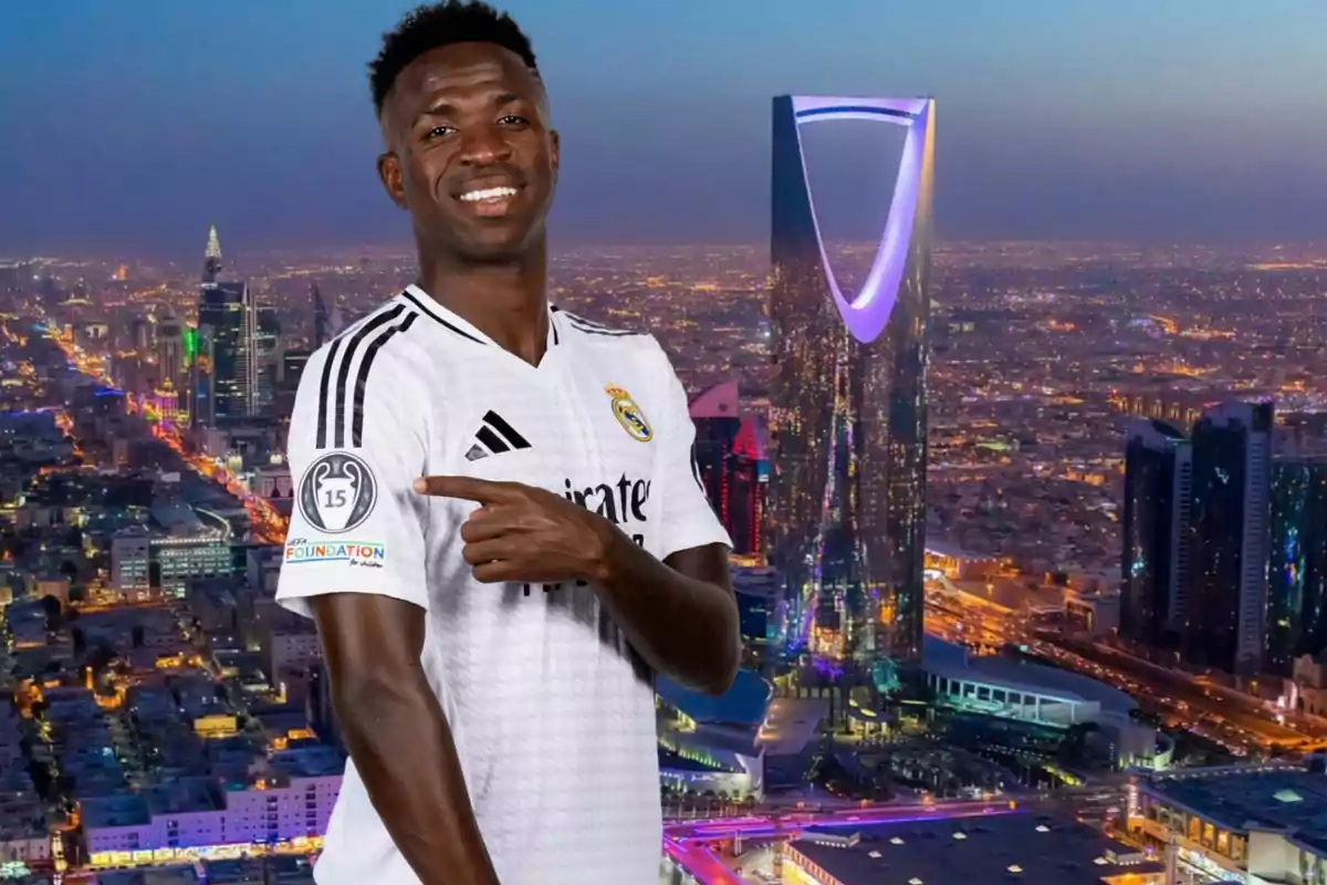 Un jugador de fútbol con la camiseta del Real Madrid sonríe y señala un parche en su manga con un paisaje urbano iluminado al anochecer de fondo.