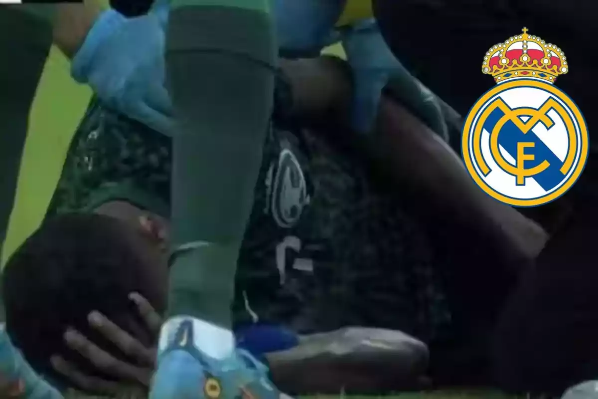 Un jugador con equipacion verde en el suelo tapándose la cara y el escudo del Real Madrid al lado