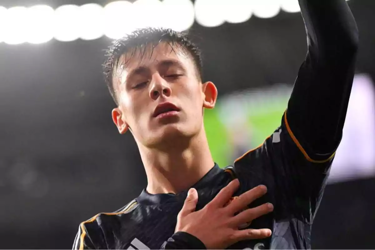 Un jugador de fútbol con los ojos cerrados y la mano en el pecho durante un partido.