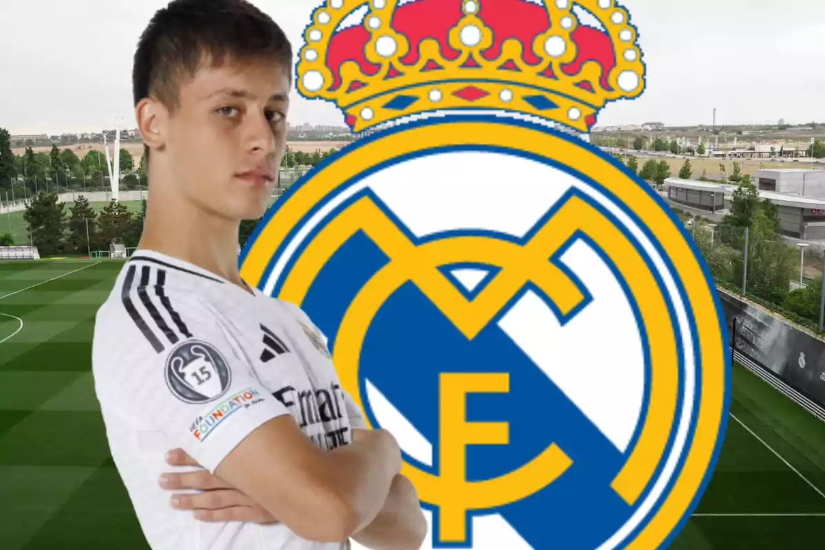 Un jugador de fútbol con la camiseta del Real Madrid posando frente al escudo del club en un campo de entrenamiento.