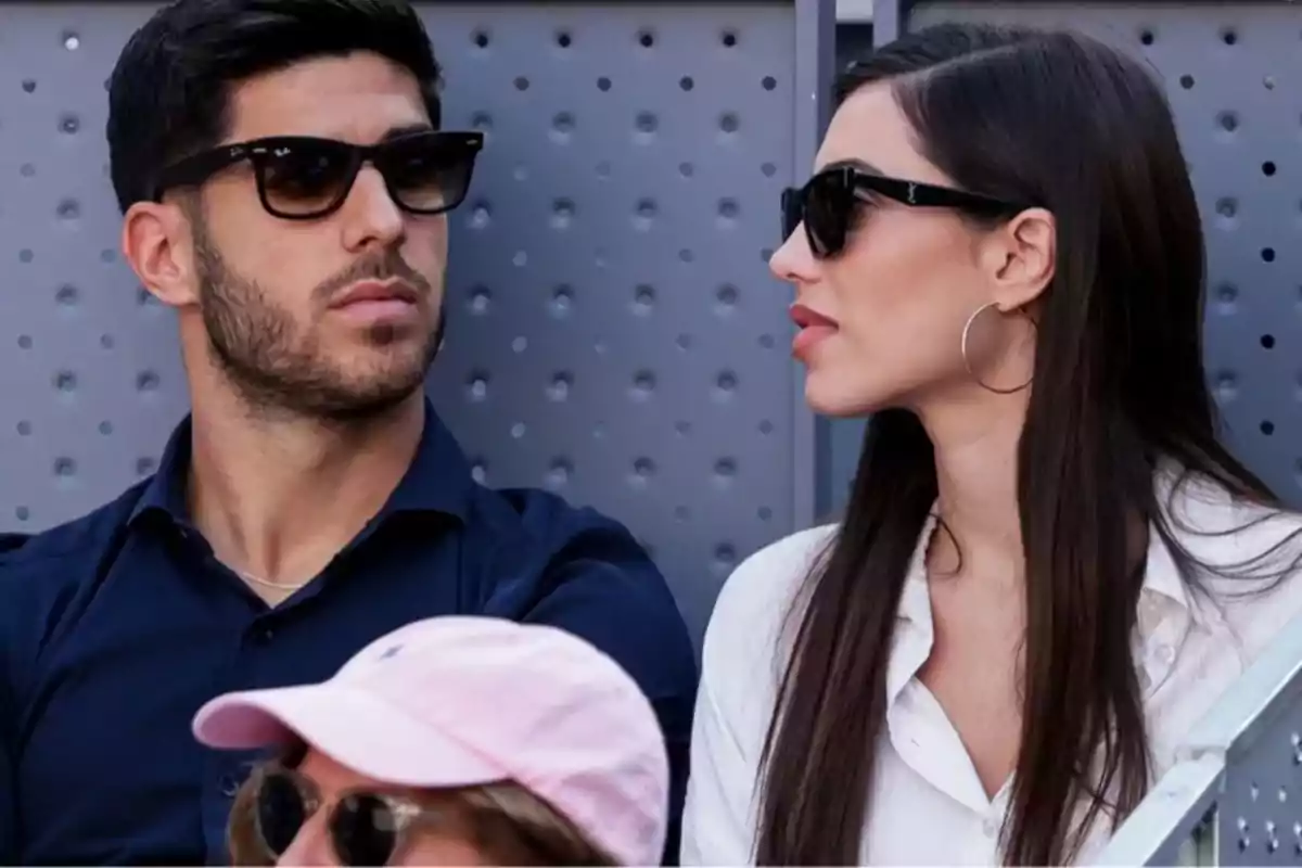 Dos personas con gafas de sol sentadas una al lado de la otra, mirando en direcciones opuestas.