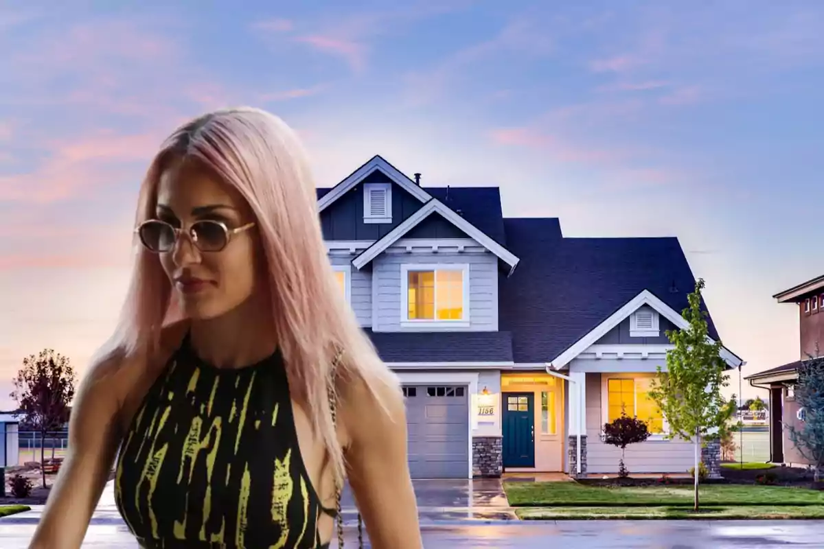 Una mujer con cabello rosado y gafas de sol está frente a una casa moderna al atardecer.