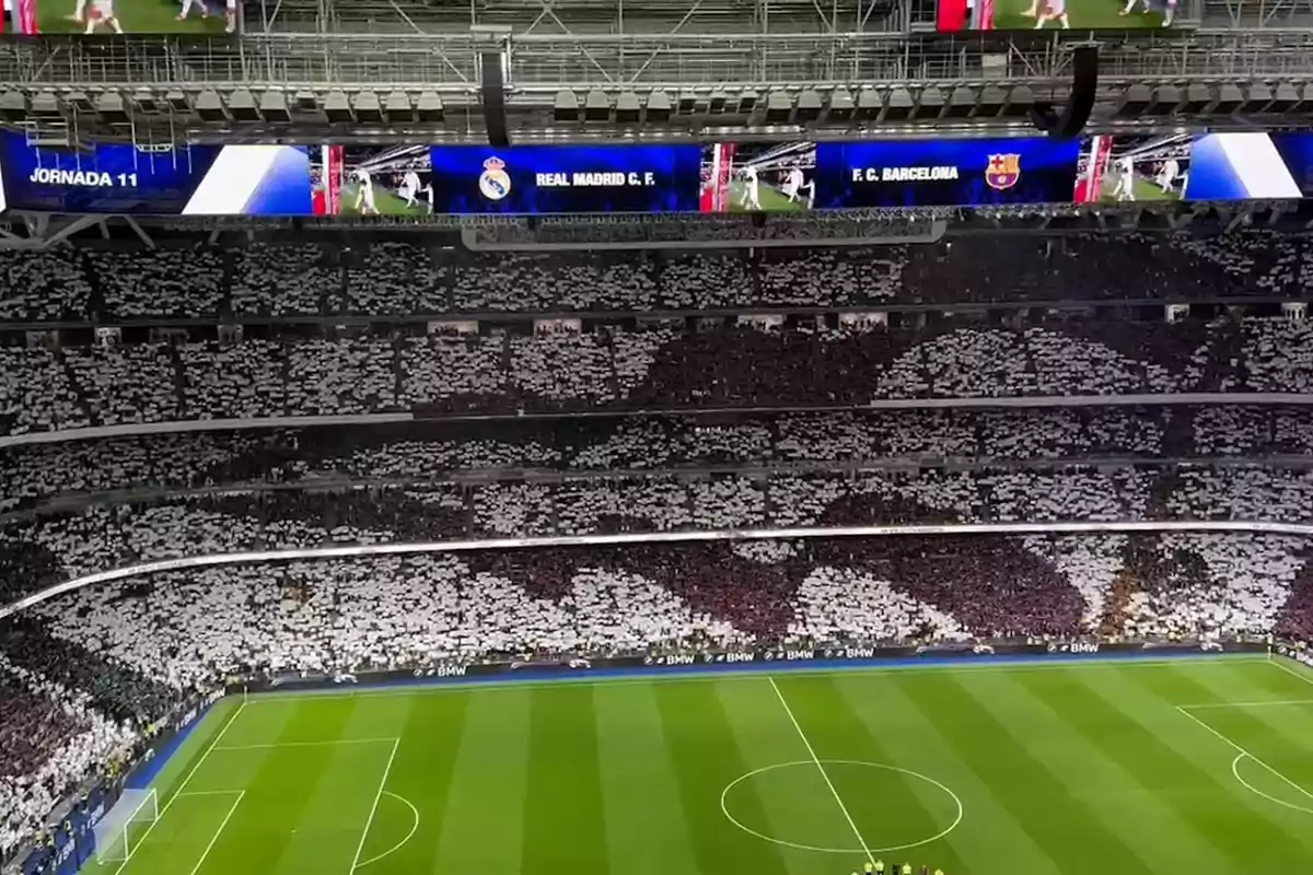 Un estadio de fútbol lleno de aficionados con mosaicos en las gradas durante un partido entre el Real Madrid y el FC Barcelona.