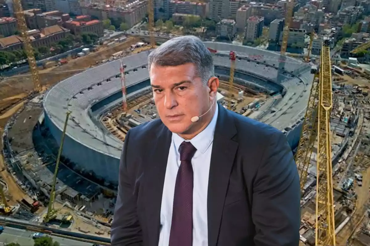 Un hombre con traje y micrófono está frente a un estadio en construcción.