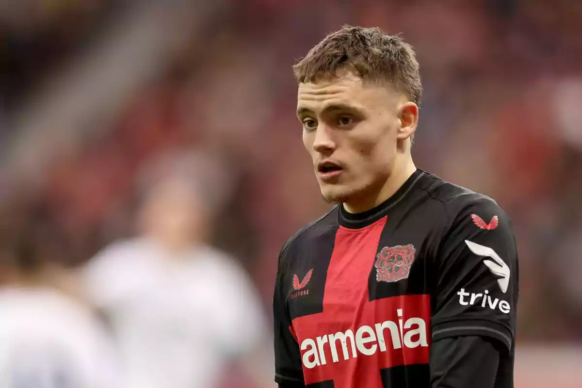 Un jugador de fútbol con uniforme negro y rojo en el campo de juego.