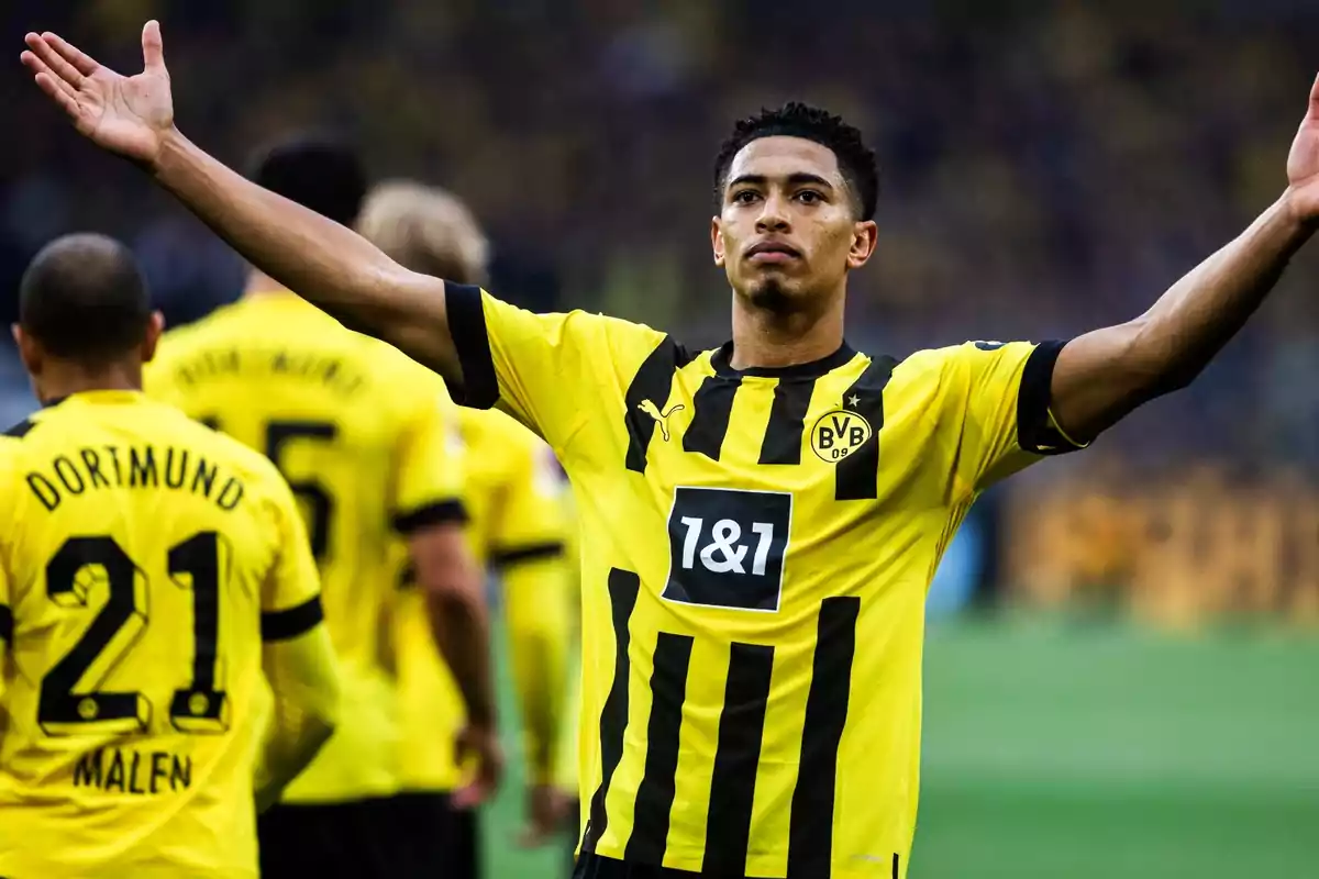 Jugador del Borussia Dortmund celebrando con los brazos extendidos mientras otros jugadores del equipo están en el fondo.