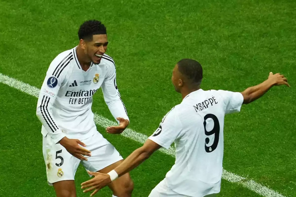 Dos jugadores de fútbol del Real Madrid celebrando en el campo.