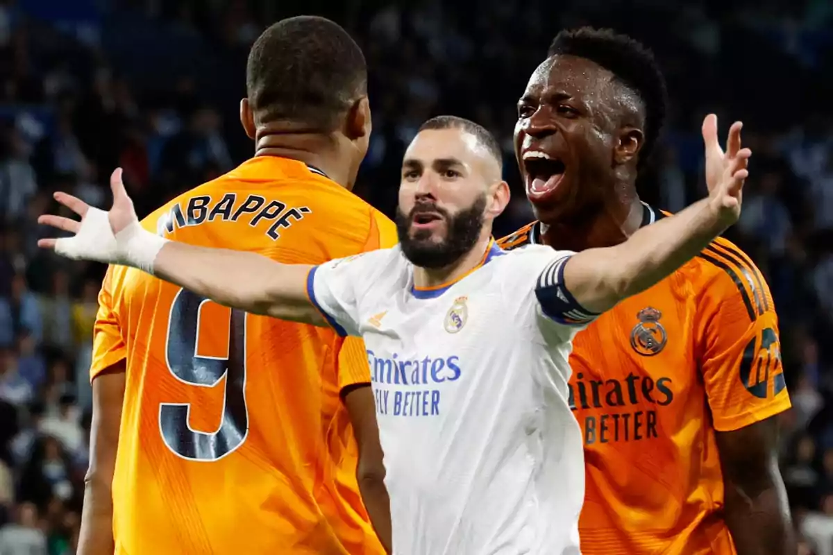 Tres jugadores de fútbol en el campo, uno de ellos con los brazos extendidos y expresión de celebración.