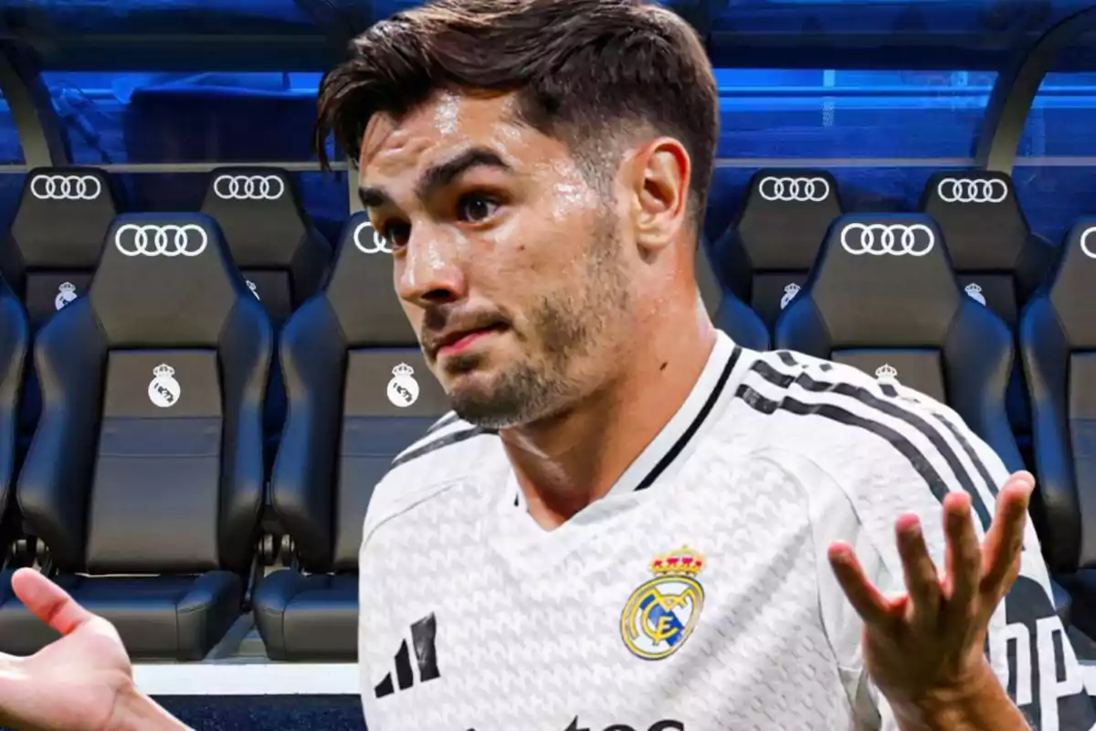 Un jugador de fútbol con la camiseta del Real Madrid gesticulando con los brazos levantados, con el banquillo del equipo de fondo.