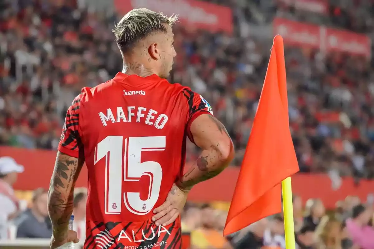 Jugador de fútbol con la camiseta número 15 junto a una bandera de esquina en un estadio.